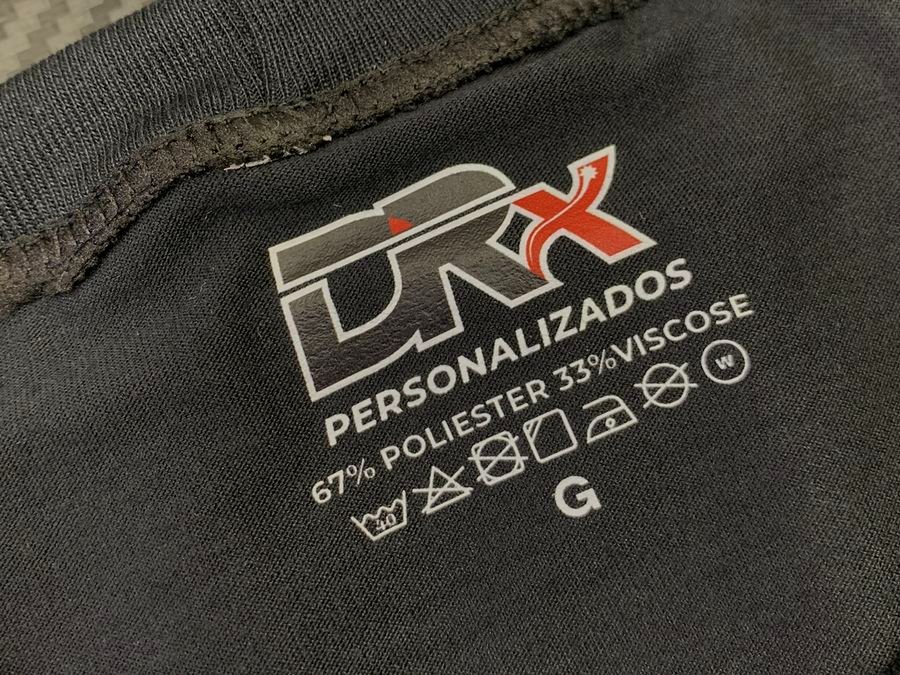 Etiqueta DRx Personalizados na gola de uma camiseta preta, indicando 67% poliéster e 33% viscose